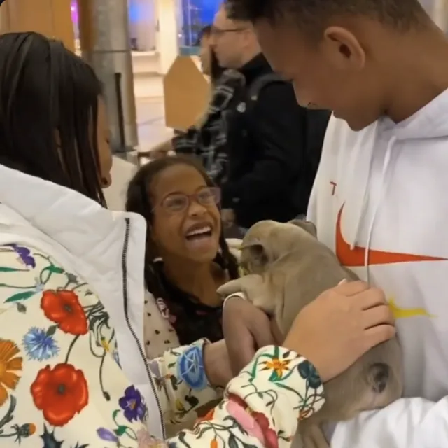 Smiling girl meeting her new Frenchie puppy at the airport